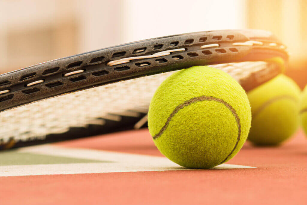tennis racquet resting on tennis ball