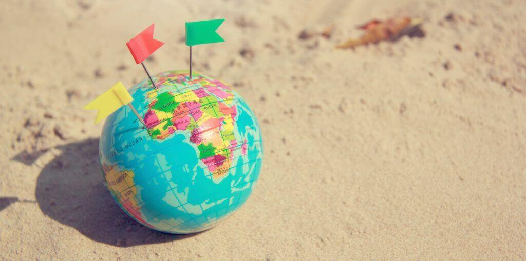 globe with coloured flags in on the beach