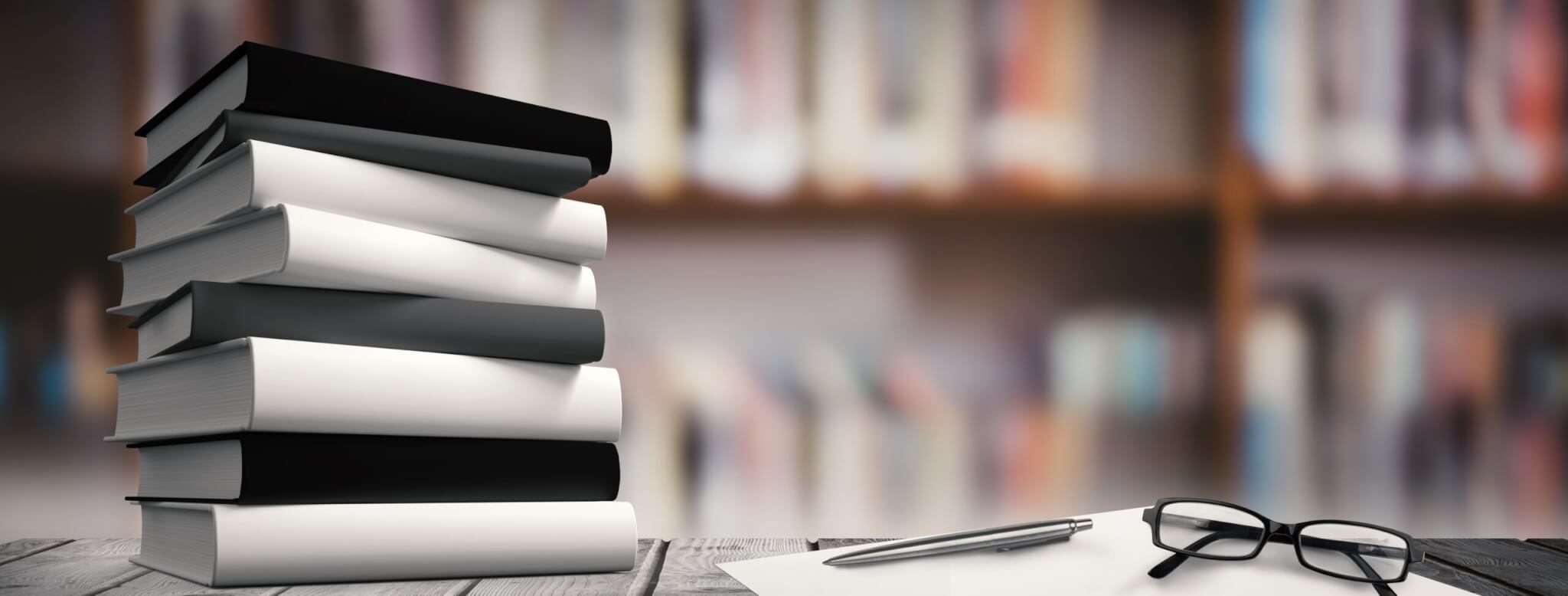stack of books on desk with glasses